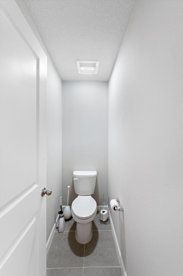 bathroom with tile patterned flooring, a textured ceiling, and toilet