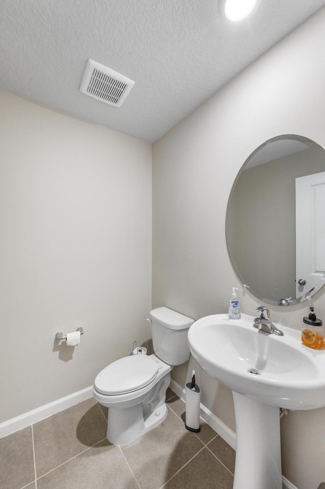 bathroom with tile patterned flooring, a textured ceiling, and toilet