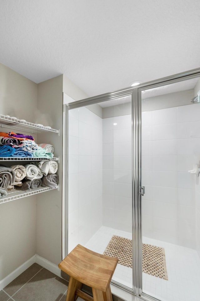 bathroom featuring tile patterned floors, walk in shower, and a textured ceiling