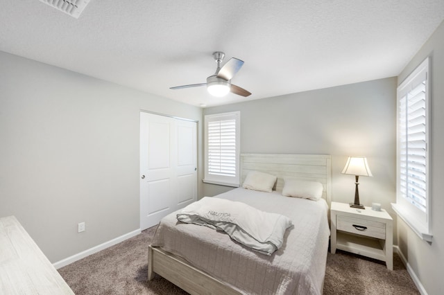 carpeted bedroom featuring ceiling fan, a textured ceiling, and multiple windows