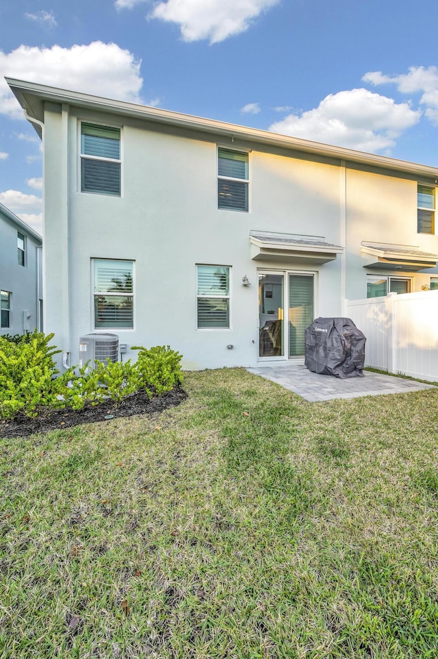 rear view of house with a lawn, central AC, and a patio