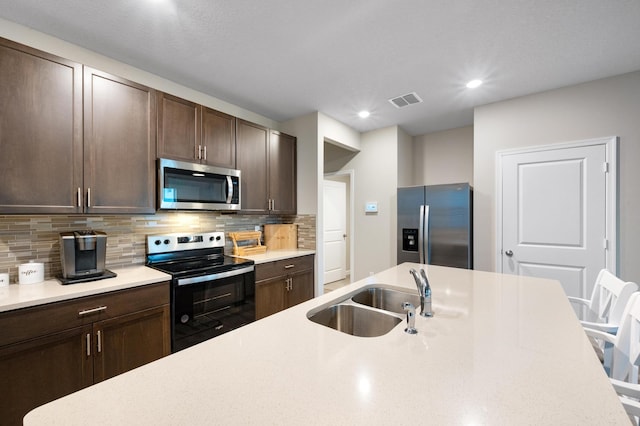 kitchen featuring backsplash, dark brown cabinetry, sink, and appliances with stainless steel finishes