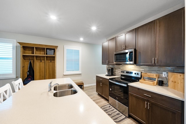 kitchen featuring backsplash, dark brown cabinetry, stainless steel appliances, sink, and light hardwood / wood-style floors