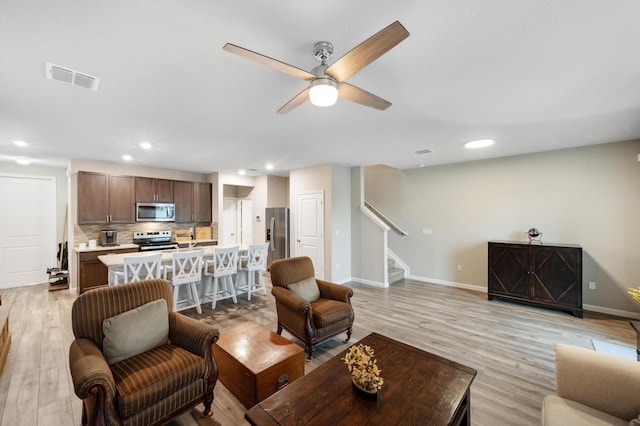 living room with ceiling fan and light hardwood / wood-style floors