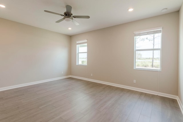 spare room with light hardwood / wood-style flooring, ceiling fan, and a healthy amount of sunlight