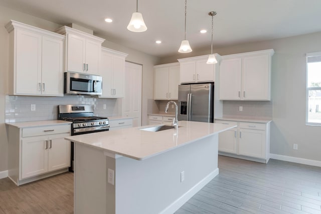 kitchen featuring pendant lighting, sink, a center island with sink, white cabinetry, and appliances with stainless steel finishes