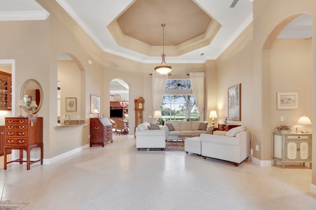 living room featuring ornamental molding, a towering ceiling, a raised ceiling, and light tile patterned floors