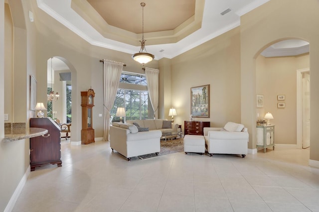 8732 Bally Bunion Rd, Port Saint Lucie, FL 34986 - living area with arched walkways, crown molding, light tile patterned flooring, a tray ceiling, and baseboards