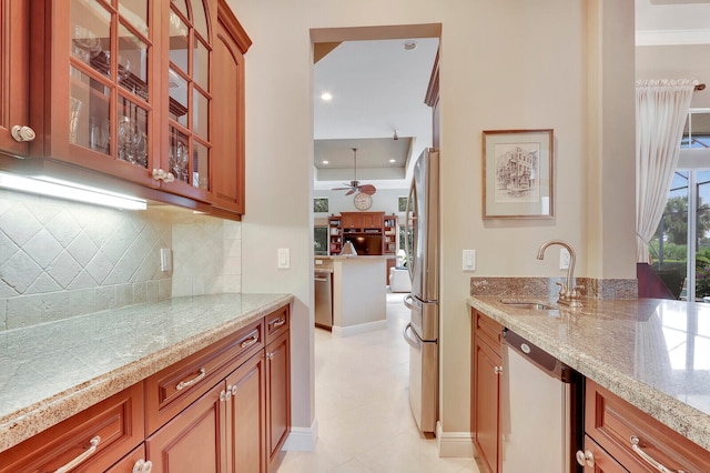 kitchen with backsplash, light stone counters, appliances with stainless steel finishes, and sink