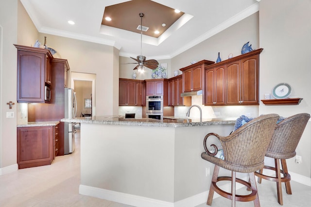 kitchen with ceiling fan, sink, kitchen peninsula, appliances with stainless steel finishes, and light stone countertops