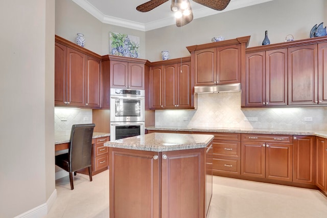 kitchen featuring stainless steel double oven, a kitchen island, backsplash, ornamental molding, and ceiling fan