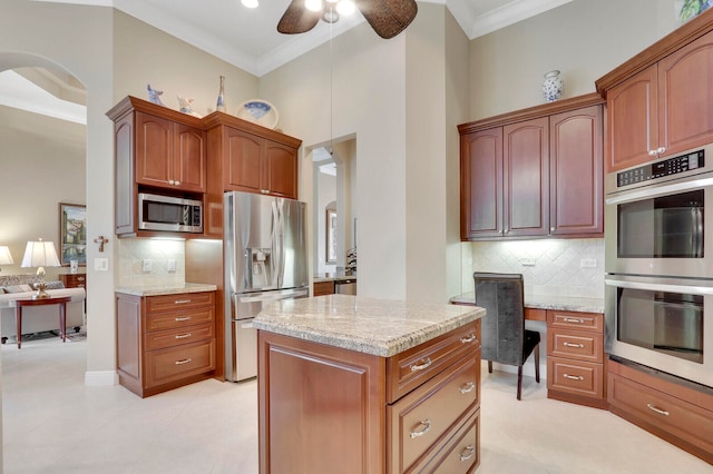 kitchen with light stone counters, appliances with stainless steel finishes, ornamental molding, a high ceiling, and ceiling fan