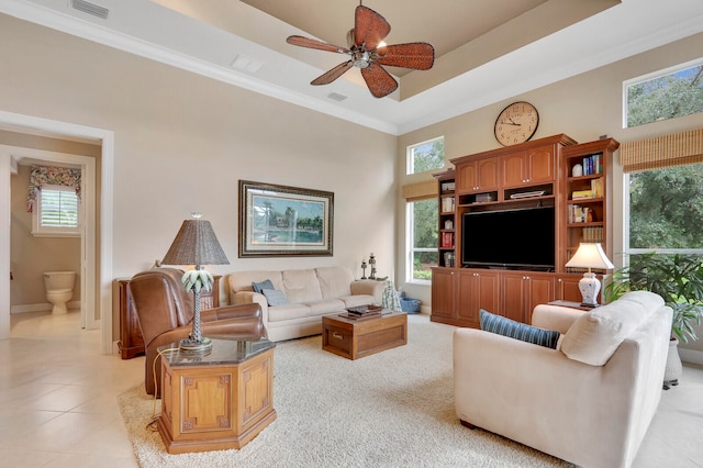 tiled living room featuring ceiling fan, a towering ceiling, ornamental molding, and a healthy amount of sunlight