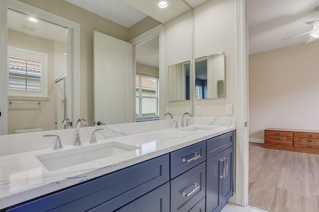 bathroom featuring ceiling fan, vanity, wood-type flooring, walk in shower, and toilet