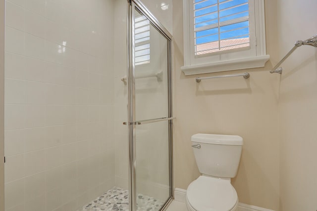 bathroom featuring toilet and a shower with door