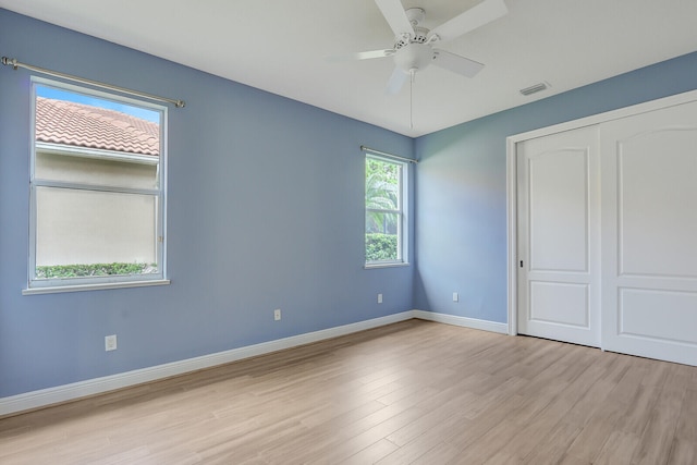 unfurnished bedroom featuring ceiling fan, light hardwood / wood-style flooring, a closet, and multiple windows