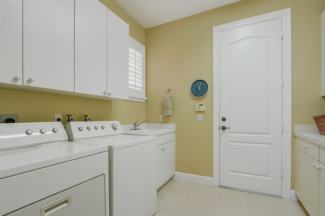 laundry area featuring light tile patterned flooring, sink, washing machine and clothes dryer, and cabinets