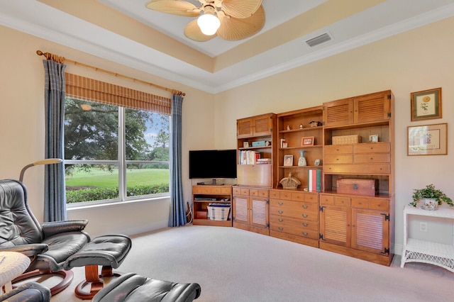 carpeted living room featuring a tray ceiling, ceiling fan, and crown molding