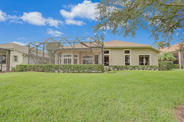 rear view of house with a lawn and a lanai