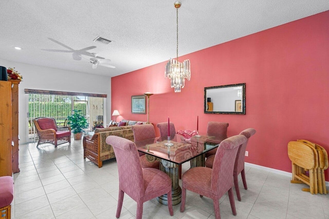 tiled dining area featuring a textured ceiling and ceiling fan with notable chandelier