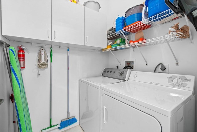 clothes washing area featuring cabinets and washing machine and clothes dryer