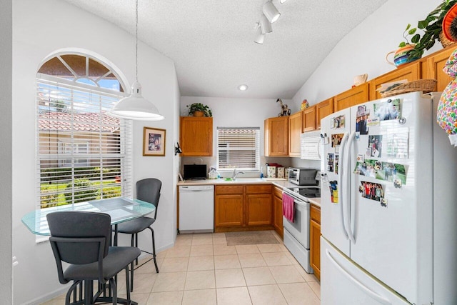 kitchen with pendant lighting, a textured ceiling, light tile patterned flooring, vaulted ceiling, and white appliances