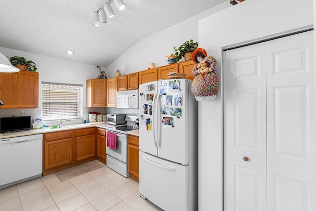 kitchen featuring a textured ceiling, lofted ceiling, light tile patterned floors, and white appliances