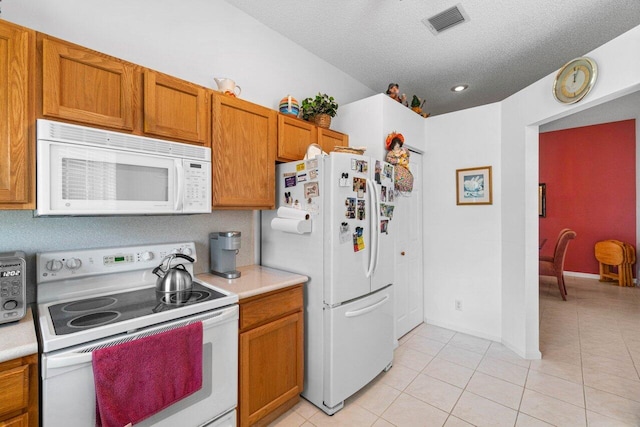 kitchen with white appliances, a textured ceiling, and light tile patterned floors