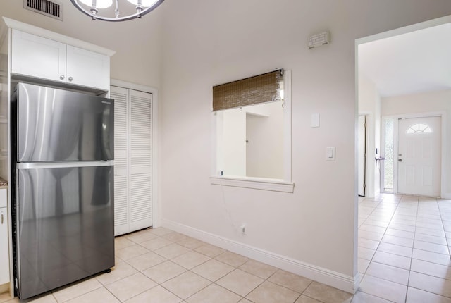 kitchen with light tile patterned flooring, white cabinetry, and stainless steel fridge