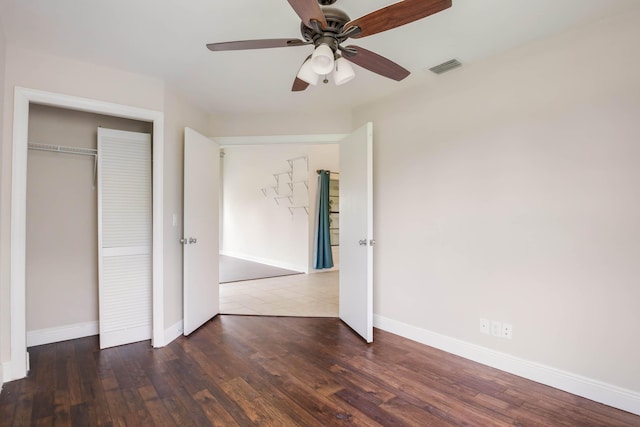 unfurnished bedroom with ceiling fan, dark hardwood / wood-style floors, and a closet