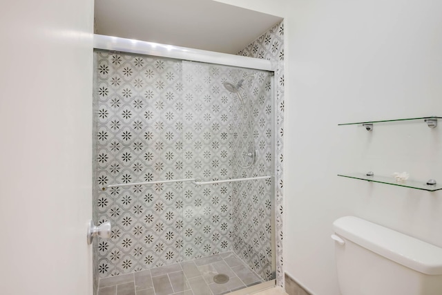 bathroom featuring a shower with shower door, toilet, and tile patterned flooring