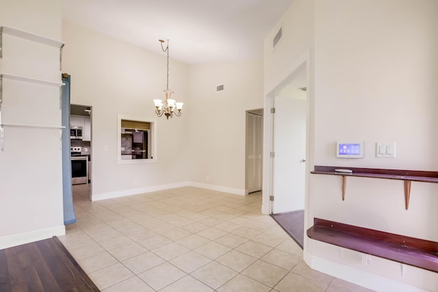 interior space featuring an inviting chandelier, light tile patterned flooring, and high vaulted ceiling