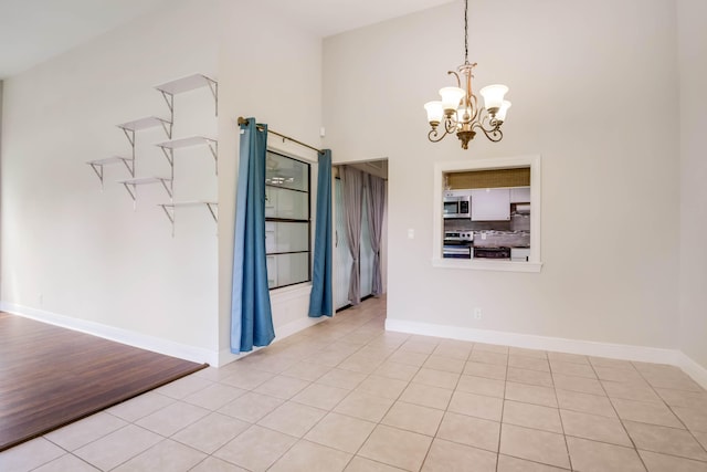 tiled empty room featuring a notable chandelier, a towering ceiling, and a barn door