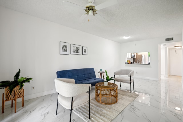 sitting room featuring ceiling fan and a textured ceiling