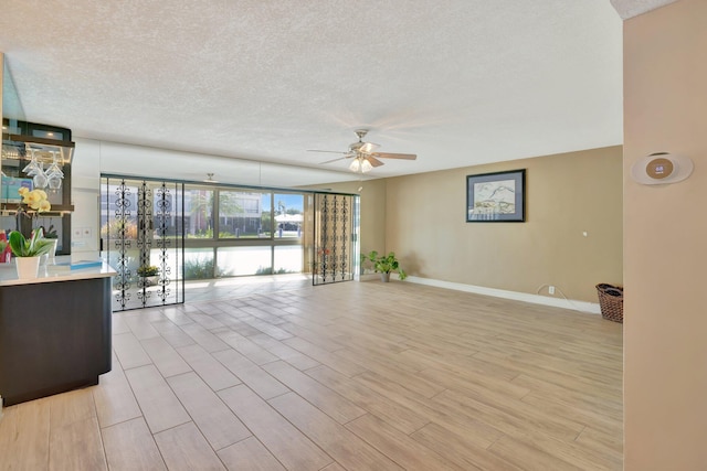 living room featuring a wall of windows, a textured ceiling, light wood-type flooring, and ceiling fan