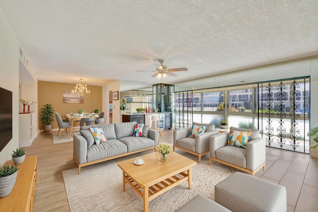 living room with a textured ceiling, ceiling fan with notable chandelier, and light hardwood / wood-style floors