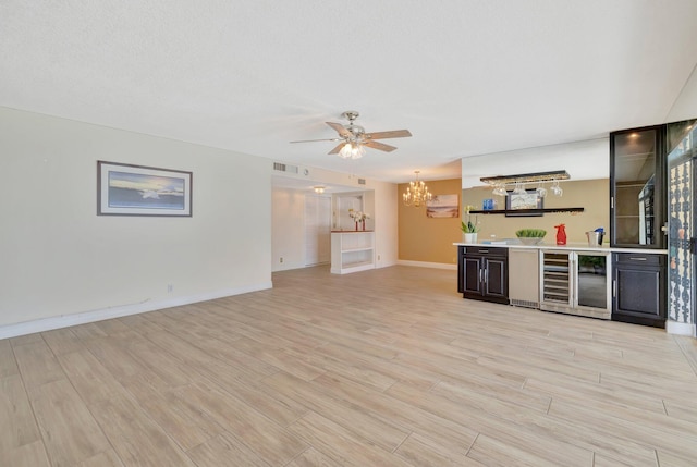 unfurnished living room with light hardwood / wood-style floors, bar area, beverage cooler, and ceiling fan with notable chandelier