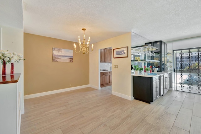 kitchen with light hardwood / wood-style floors, a notable chandelier, and a textured ceiling