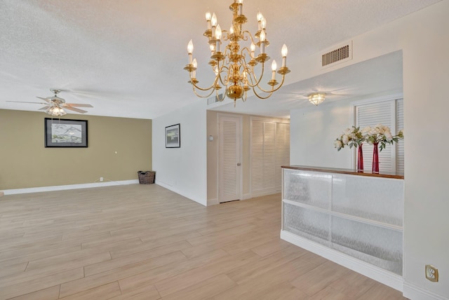 unfurnished room with ceiling fan with notable chandelier, a textured ceiling, and light hardwood / wood-style floors