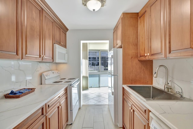 kitchen with white appliances, tasteful backsplash, light stone countertops, and sink