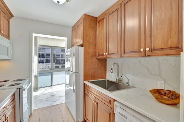 kitchen featuring tasteful backsplash, sink, light stone counters, and white appliances