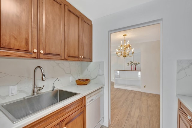 kitchen featuring tasteful backsplash, sink, dishwasher, light hardwood / wood-style floors, and a notable chandelier