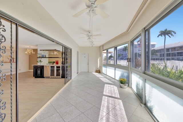 sunroom with wine cooler, vaulted ceiling, and ceiling fan with notable chandelier