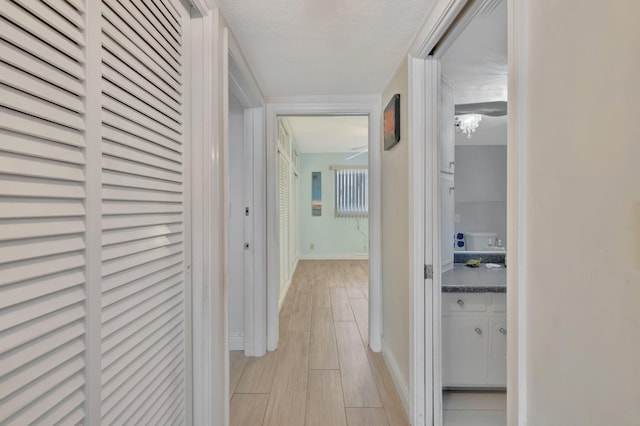 hall featuring light hardwood / wood-style flooring and a textured ceiling