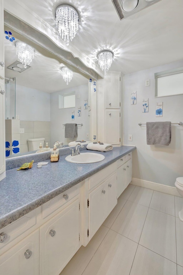 bathroom featuring vanity, toilet, tile patterned floors, and decorative backsplash