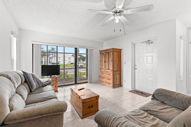 living room with ceiling fan, a textured ceiling, and light tile patterned flooring