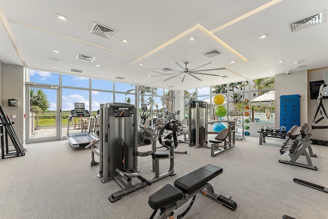 exercise room featuring ceiling fan, expansive windows, and light colored carpet