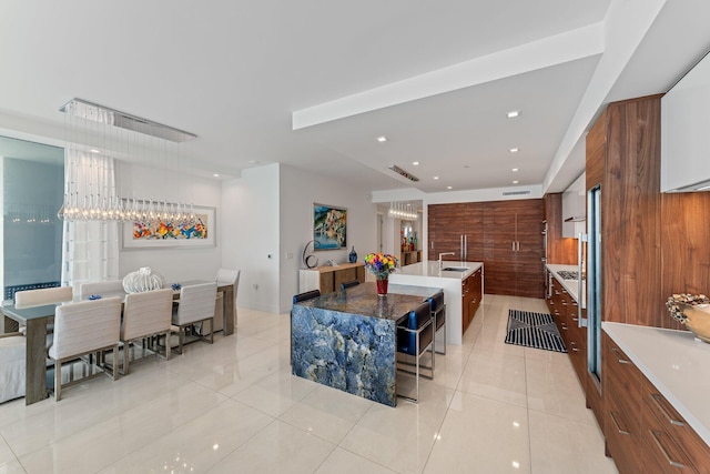 kitchen featuring wooden walls, a kitchen island with sink, sink, and light tile patterned floors