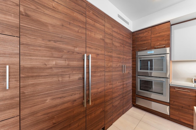 kitchen featuring stainless steel double oven and light tile patterned floors