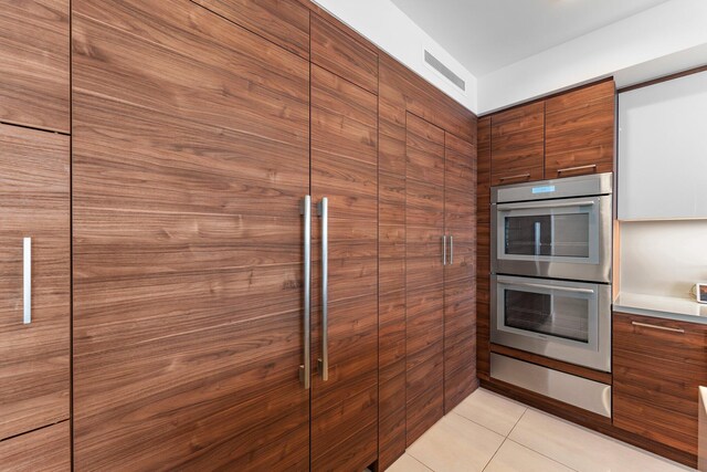 5000 N Ocean Dr Unit 1003, Singer Island, FL 33404 - kitchen with stainless steel double oven, modern cabinets, light countertops, light tile patterned floors, and brown cabinetry